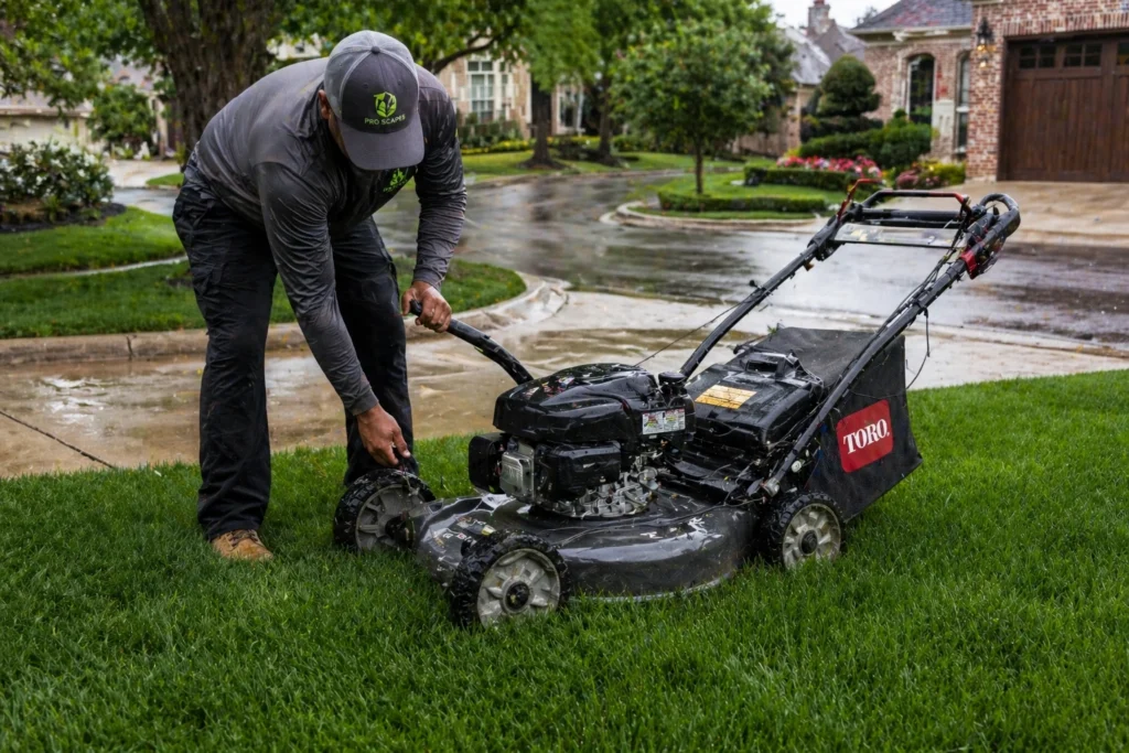 Professional landscaper adjusting mower height before cutting wet grass